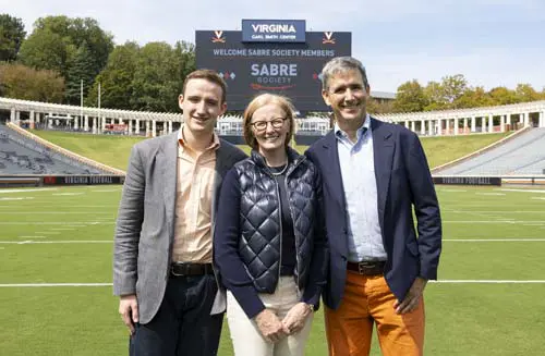 Two men and a women posing on the field
